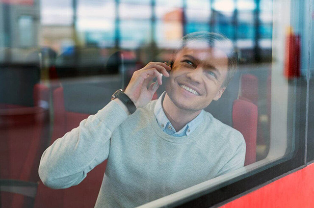 Mann sitzt am Busfenster und telefoniert
